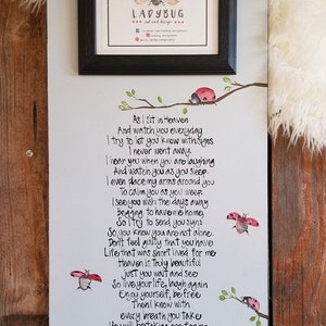 May include: A white wooden sign with a poem about loss and grief. The poem is written in black ink and features a ladybug illustration. The sign is framed with a black frame and has the words "LADYBUG artisan" at the bottom.