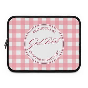 Puede incluir: Una funda rectangular para portátil con un patrón de cuadros vichy rosa y blanco. En el centro, un emblema circular blanco con texto en rosa oscuro que dice "WILLIAMS TREE INC", "God First" y "HE PAID THE ULTIMATE PRICE" con un borde fino.