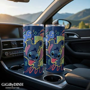 Two colorful tumblers with cartoon character designs are placed in the car's cup holder.