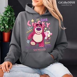 A person wearing a gray hoodie with a cartoon bear design and text printed on it.