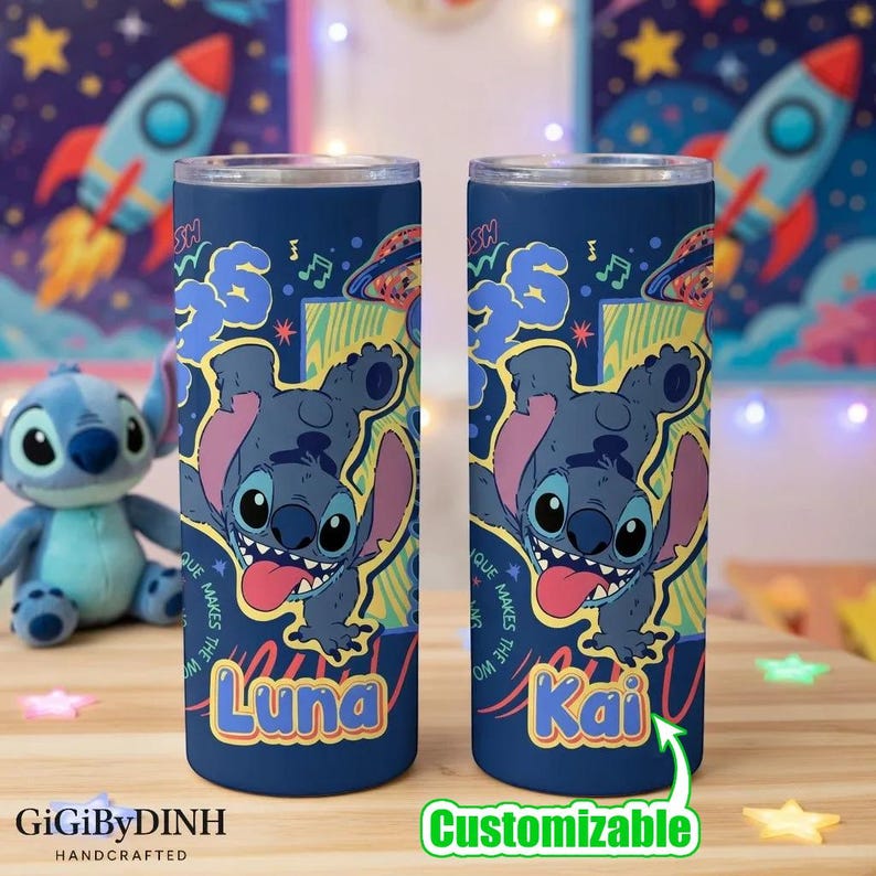 Two blue tumblers with a cartoon character design, featuring the character Luna and the name Kai, are placed on a wooden surface. In the background, there is a stuffed animal and a space-themed background with a rocket ship.