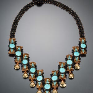 May include: A handcrafted necklace featuring a black beaded chain with turquoise and gold accents. The necklace has turquoise center stones, gold teardrop pendants, and a black crystal drop. The necklace is a statement piece.