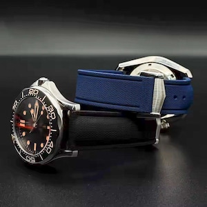 May include: Two stainless steel watches with black and blue bands. The watch faces are black with luminous markers and hands. The bezels are black with white numerals. The bands are made of a textured material.