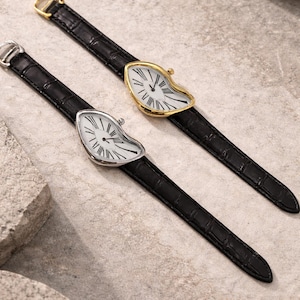 May include: Two unique wristwatches with a melting clock face design. One watch has a silver case, the other is gold-toned. Both have black leather straps and white clock faces with black Roman numerals.