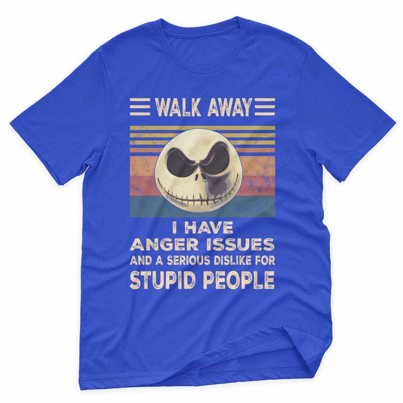 May include: Blue t-shirt with a graphic featuring a skull with a sinister expression. The text reads "WALK AWAY" above the skull and "I HAVE ANGER ISSUES AND A SERIOUS DISLIKE FOR STUPID PEOPLE" below.