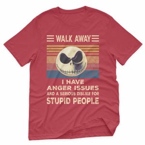 May include: Red t-shirt featuring a graphic of a skull with the text "WALK AWAY" above and "I HAVE ANGER ISSUES AND A SERIOUS DISLIKE FOR STUPID PEOPLE" below. The skull has a black eye and a sinister grin.