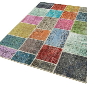 May include: A rectangular patchwork rug with a variety of colors, including teal, pink, orange, and blue. The rug is made up of many rectangular patches of different colors and patterns. The rug has a cream-colored border.
