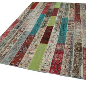 Puede incluir: Una alfombra rectangular de patchwork con una variedad de colores y patrones. La alfombra presenta rayas verticales de diferentes texturas y diseños, incluyendo motivos florales, geométricos y abstractos. Los colores incluyen rojo, verde, azul y beige.