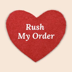 May include: A red heart-shaped felt with the words "Rush My Order" in white, centred on a light beige background. The heart has a textured appearance.