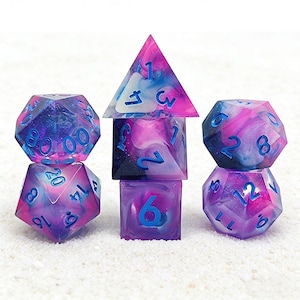 May include: A collection of seven multi-sided dice for role-playing games. The dice are in various shapes, including a d20, d12, d10, d8, d6, d4, and a d10 percentile. They feature a mix of purple, pink, and blue with blue numerals.