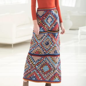 May include: A long, colorful crochet skirt featuring a geometric pattern in shades of red, blue, tan, and black. The skirt has a fitted waistband and a flared silhouette. The crochet work appears to be intricate and detailed, creating a textured look.