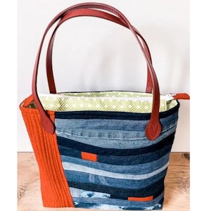 May include: A handmade tote bag with a patchwork design. The bag features a combination of denim and orange corduroy panels. It has red leather handles and a green and white polka dot lining. The bag is designed for everyday use.