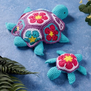 May include: Two crocheted turtle plushies. The larger turtle has a purple shell with floral designs in red, yellow, and white. The smaller turtle has a similar design. Both turtles are turquoise blue.