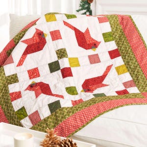 May include: A handmade quilt featuring a cardinal bird design. The quilt has a white background with red cardinal appliqués, and red, green, and yellow square accents. The border is red with white polka dots and green with a leaf pattern.