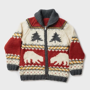 Op de afbeelding: Een gebreide vest met ritssluiting met een winterthema. De trui heeft een crèmekleurig lijfje met rode mouwen en een rood onderstuk. Het heeft een grijze kraag en boord, met een patroon van witte beren en donkergroene bomen.