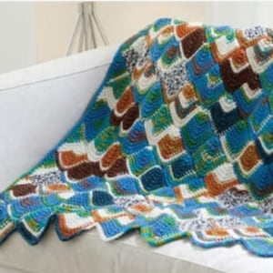 May include: A colorful, handmade crochet blanket with a geometric pattern. The blanket features squares in shades of blue, brown, white, and green. The edge has a scalloped design, adding a decorative touch. This cozy blanket is perfect for home decor.