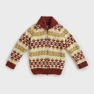 Könnte beinhalten: Eine cremefarbene Strickjacke mit Reißverschluss und einem geometrischen Muster in Burgunder- und Goldtönen. Der Pullover hat einen bordeauxfarbenen Kragen und Bündchen. Das Design zeigt ein sich wiederholendes Muster aus rauten- und sternartigen Formen.