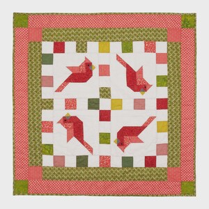 K&ouml;nnte beinhalten: Ein quadratischer Quilt mit vier roten Kardinalvogel-Designs auf wei&szlig;em Hintergrund. Der Quilt hat einen roten und gr&uuml;nen Rand mit einem Tupfenmuster. Die V&ouml;gel sind aus rotem Stoff mit gelben Schn&auml;beln.