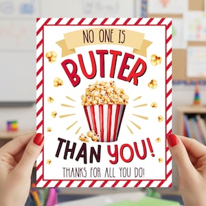May include: A rectangular card with a red and white striped border and the words "NO ONE IS BUTTER THAN YOU! THANKS FOR ALL YOU DO!" in a playful font. The card features a popcorn graphic.