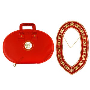 May include: A red oval-shaped carrying case with a handle and a gold emblem, next to a red and gold ceremonial collar. The case has the text "Heroines of Jericho" and "Masonic Hub". The collar is adorned with gold symbols and a gold chain.