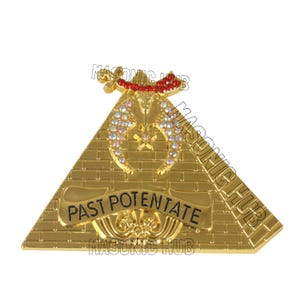 以下が含まれることがあります： 金色のフリーメーソンエンブレム。ピラミッド型で、黒い文字で「PAST POTENTATE」と書かれています。三日月と星のデザインで、クリアと赤の宝石が飾られています。「MASONIC HUB」の文字も見えます。