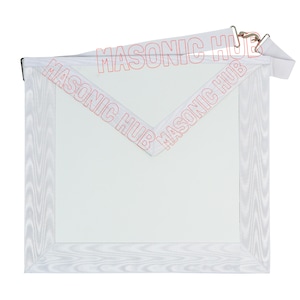 May include: A white Masonic apron with a decorative border and the text "MASONIC HUB" in red. The apron has a white ribbon and metal clasps at the top. The apron is square-shaped with a V-shaped flap.