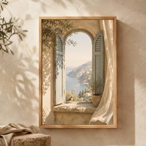 Puede incluir: Una impresión de arte mural rectangular en un marco de madera clara que representa una ventana arqueada con contraventanas azul pálido abiertas. La vista muestra un paisaje costero con un pequeño pájaro en el alféizar y una planta en maceta.