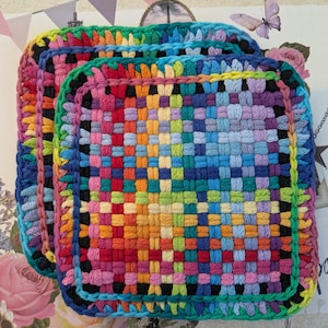 May include: A stack of three square, woven potholders in a rainbow of colors. The potholders are made of yarn and have a woven pattern. The edges are finished with a contrasting color, and the overall effect is bright and cheerful.