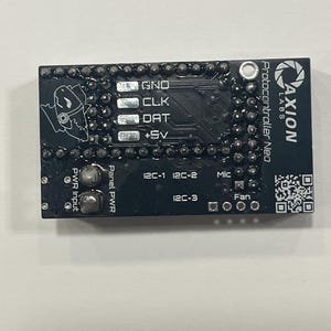 May include: A black Protocontroller Neo circuit board with white text and a logo. The board has various connection points labeled GND, CLK, DAT, and +5V. Additional labels include PWR Input, Panel PWR, I2C-1, I2C-2, I2C-3, Mic, and Fan.