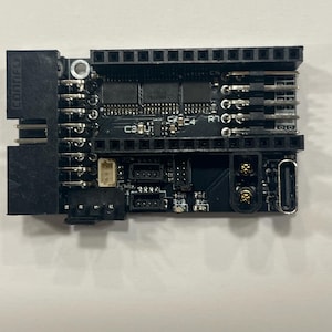 May include: A black circuit board with various electronic components, including chips, connectors, and pins. The board has the text "CONIFLY" printed on the side. It features multiple ports and a USB-C connector.