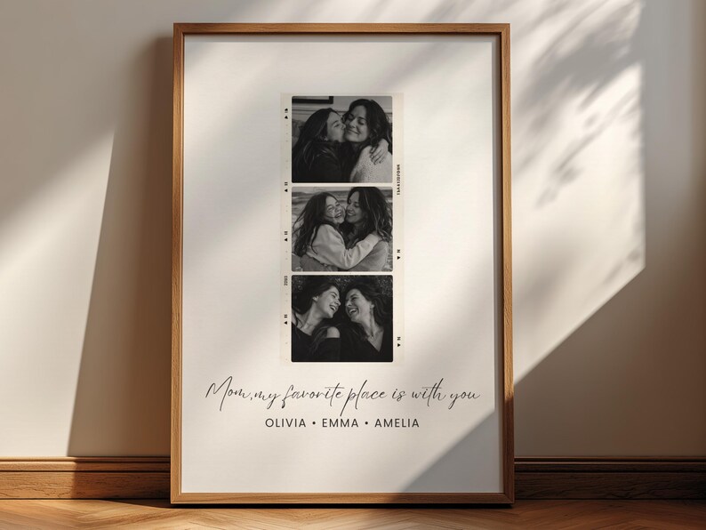 May include: A framed black and white print featuring three vertical filmstrip-style photos of two people embracing. The print includes the text "Mom, my favorite place is with you" and the names Olivia, Emma, and Amelia.