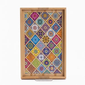Puede incluir: Bandeja rectangular de madera para servir con un diseño de mosaico de azulejos coloridos. La bandeja presenta un marco de madera marrón claro y un patrón decorativo de varios colores, incluyendo azul, naranja, rosa y verde. Tiene asas de cuerda.
