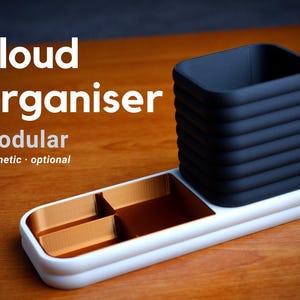 May include: A white and gold modular organizer with a black pen holder. The organizer has a rectangular base with three compartments and a cylindrical pen holder. The text "cloud organiser" is displayed.