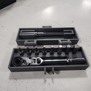 May include: A gray tool set with a ratchet, various bits, and an extension bar, neatly organized in a gray case. The case is open, revealing the tools. The tools are made of metal.