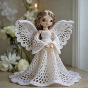 Pode incluir: Uma boneca de anjo branca de crochê, feita à mão, com asas detalhadas e um vestido esvoaçante. A boneca tem cabelo loiro e traços delicados. O anjo é um item decorativo.