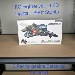May include: A box featuring an RC Fighter Jet with LED lights and 360° stunts. The box displays an image of the fighter plane with a remote control. Text on the box reads "Fighter Plane" and "Interstellar Fighter Plane Exploration of the Unknown."