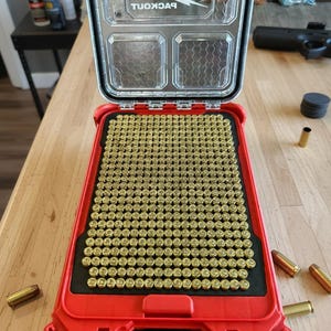 May include: A red and black organizer with a clear lid, filled with numerous brass-colored 9mm rounds. The organizer is labeled "Milwaukee" and includes the text "Slim Packout 9mm Insert - 3D Printed 450 Round Organizer for Milwauke 48-22-8456."