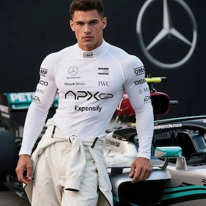 Puede incluir: Una camiseta de carreras blanca de manga larga con logotipos de patrocinadores, incluyendo "OMP", "Shark Ninja" y "Expensify". La camiseta se combina con pantalones blancos. Un coche de carreras está en el fondo. El logotipo de Mercedes-Benz es visible.