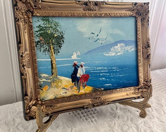 Oprawione w ramę dzieło sztuki przedstawiające nadmorski pejzaż, marynistyczny pejzaż oceaniczny, wystrój domku na plaży, ozdobna złota rama, akcent w stylu vintage