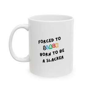 May include: White ceramic mug with a curved handle. The mug features the text "FORCED TO SLACK, BORN TO BE A SLACKER" in black and colorful letters.