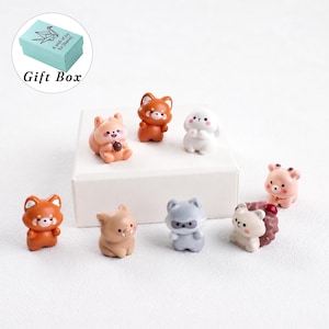 May include: A collection of eight small animal figurines including a red panda, a white rabbit, a pig, a raccoon, and a hedgehog. The set includes a light blue gift box with the text A wish of joy for [Name] printed on the lid.