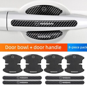 May include: An 8-piece set of black carbon fiber pattern protective stickers for a car door handle and bowl. The decals feature the Nissan logo and text. Four pieces are shaped for the door bowl and four are rectangular strips for the handle.