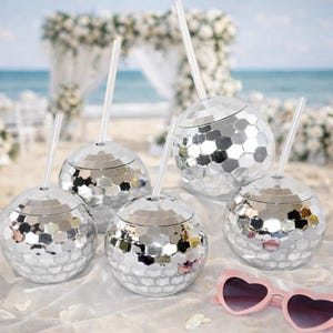 May include: A white ceramic mug with a black handle and the text "But First, Coffee" in a black, handwritten-style font. The mug is on a white surface.