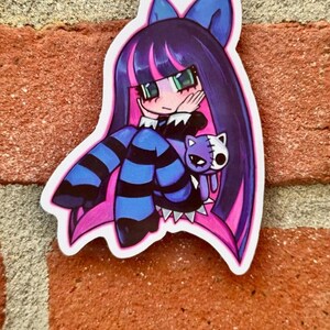 May include: A die-cut sticker depicting an anime-style character with long purple hair, pink highlights, and blue accents. The character holds a purple cat plushie. The sticker is on a brick wall.