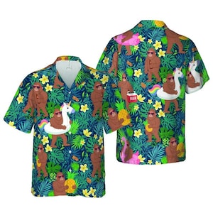 May include: Short-sleeved button-down shirt with a whimsical pattern featuring brown Bigfoot characters wearing sunglasses, floating on unicorn pool floats, and holding pineapples and beer. The background is a dark blue with green tropical leaves and yellow flowers.