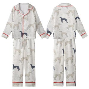 May include: White pajama set with a repeating pattern of grey and navy greyhound dog illustrations. The long-sleeved top and pants have red trim. The pajamas are made of a soft, lightweight material.