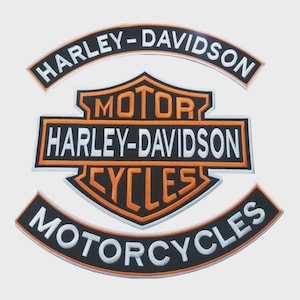 May include: Embroidered patches featuring the Harley-Davidson logo. The patches are black, orange, and white, with the words "HARLEY-DAVIDSON," "MOTOR," and "CYCLES" prominently displayed. The patches are designed for application on clothing or accessories.