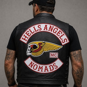 May include: Black leather vest with the "HELLS ANGELS NOMADS" patch on the back. The patch features a skull with wings and the letters "MC". The vest is worn over a black t-shirt.