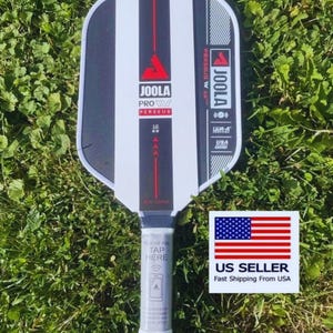 May include: A JOOLA Pro Perseus pickleball paddle with a black and white striped face. The paddle has a red accent stripe and the text "16 mm". The handle has the text "REMOVE FOL TAP HERE". A US Seller sticker is in the image.