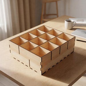May include: A light-colored wooden organizer with 12 square compartments. The organizer sits on a wooden table, with a small potted plant, a coffee cup, and a notebook in the background. The organizer is likely for small items.